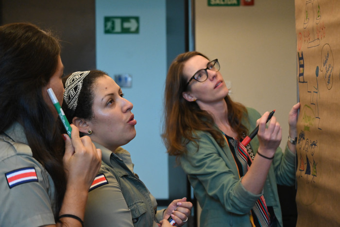 Tres mujeres al frente de una pizarra Metaplan.